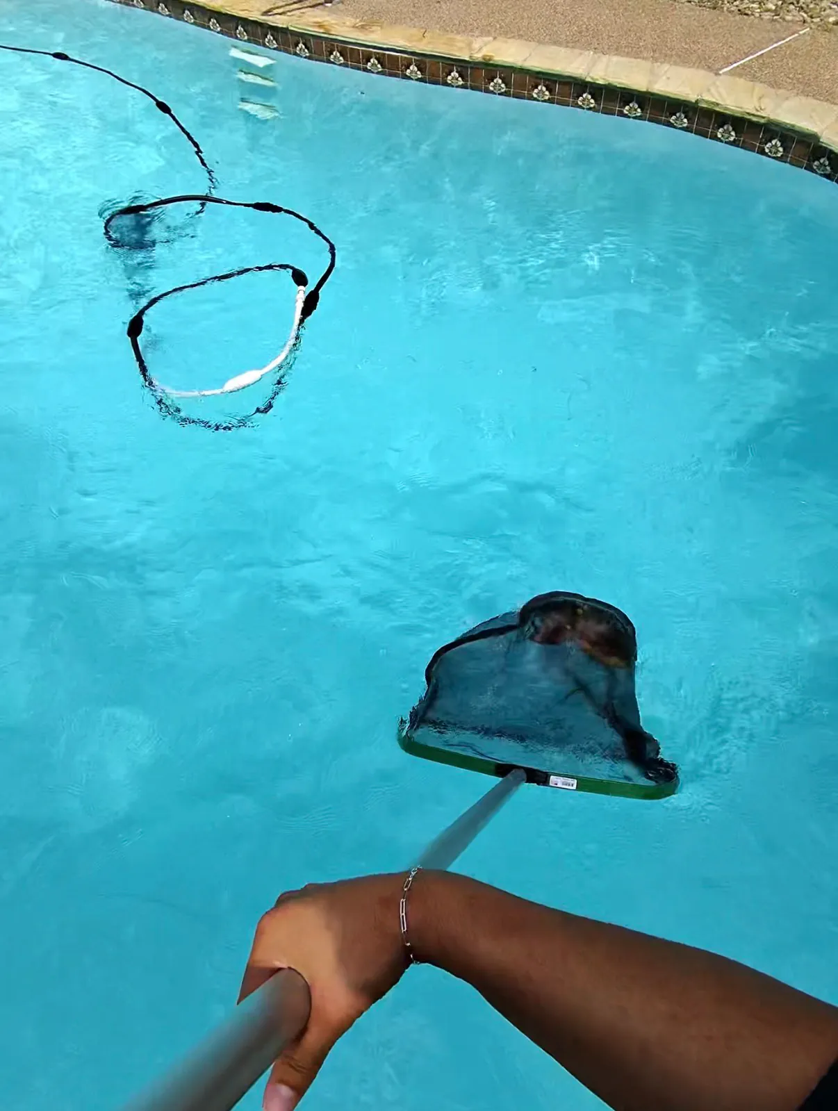 Buff Pools technician skimming a pool